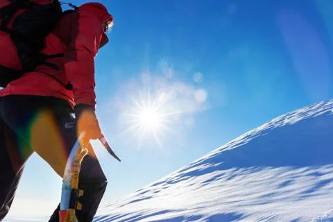 Concept: overcome challenges. Mountaineer faces a climb at the top of a sno.. Stock Photos