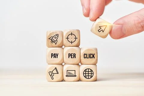 Concept Pay per click or PPC. Person stacks wooden cubes from text and icons. Stock Photos