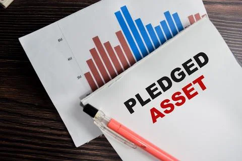 Concept of Pledged asset write on clipboard isolated on Wooden Table. Fotos de archivo
