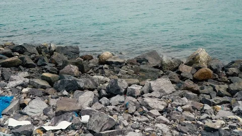The concept of pollution of nature, the environment. Stony shore and garbage  Stock Footage 108736861