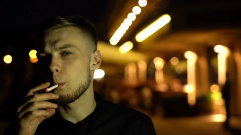 Concept portrait of young bearded man smoking cigarette at night in city Stock Footage 117631802