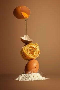 Concept poster. Broken egg falls down into flour with pasta on it. The egg is Stock Photos