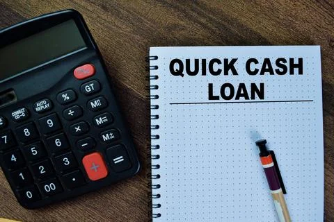 Concept of Quick Cash Loan write on book isolated on Wooden Table. Fotos Stock