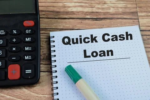 Concept of Quick Cash Loan write on book isolated on Wooden Table. Fotos Stock