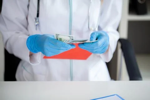 The concept of receiving payment by doctors, red envelope with dollars on the Stock Photos