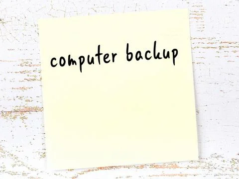 Concept of reminder about computer backup. Yellow sticky sheet of paper on wo Stock Photos
