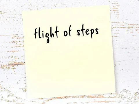 Concept of reminder about flight of steps. Yellow sticky sheet of paper on wo Фото