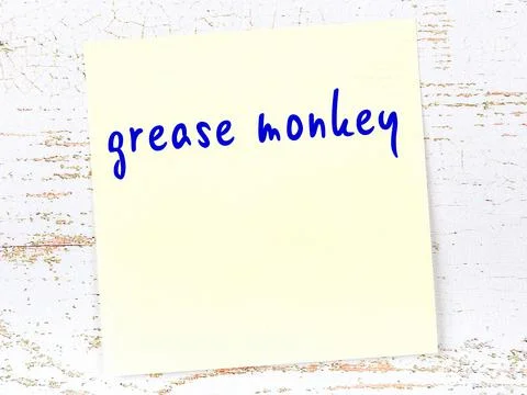 Concept of reminder about grease monkey. Yellow sticky sheet of paper on wood 写真素材