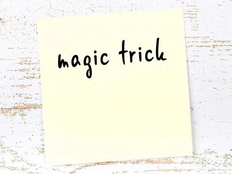 Concept of reminder about magic trick. Yellow sticky sheet of paper on wooden 写真素材