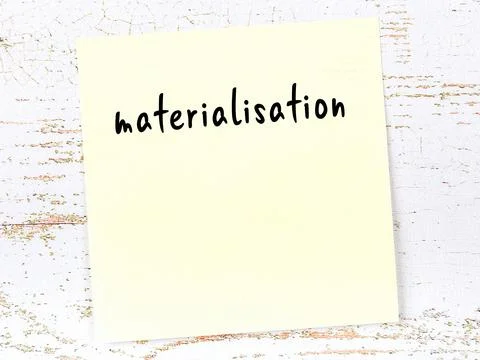 Concept of reminder about materialisation. Yellow sticky sheet of paper on wo 库存照片