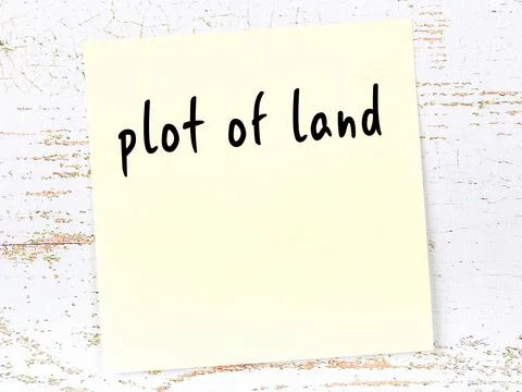 Concept of reminder about plot of land. Yellow sticky sheet of paper on woode Fotos de archivo