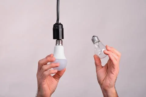The concept of replacing an incandescent light bulb with an LED lamp. Stock Photos