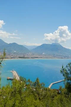 Concept of rest. Sea surface with clouds on horizon and costline town with Stock Photos