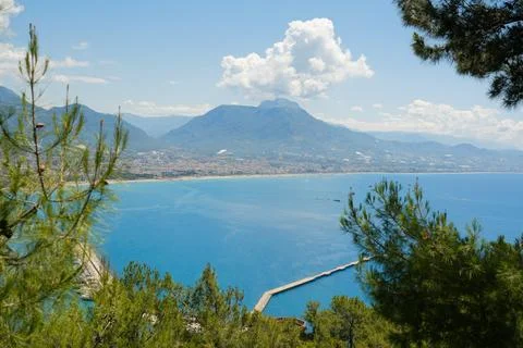 Concept of rest. Sea surface with clouds on horizon and costline town with Stock Photos