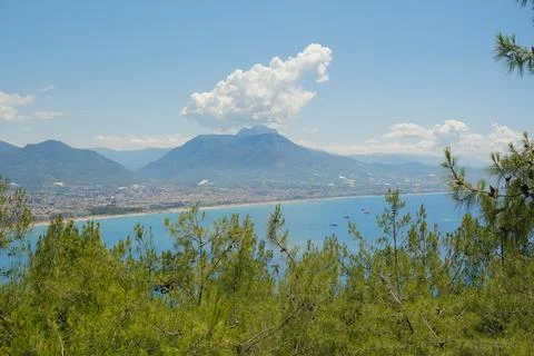 Concept of rest. Sea surface with clouds on horizon and costline town with Stock Photos