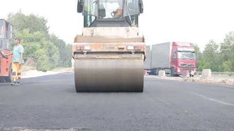 The concept of road construction works. Rolling of fresh hot asphalt. Video stock 225921269