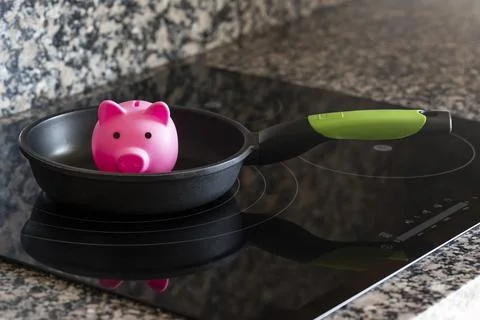 Concept of saving electricity consumption in a kitchen with a piggy bank Stock Photos