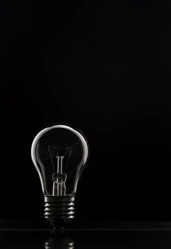 The concept of saving electricity. A tungsten light bulb on a black background. Stock Photos