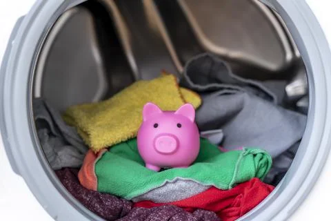 Concept of saving electricity with a washing machine with a piggy bank inside Stock Photos