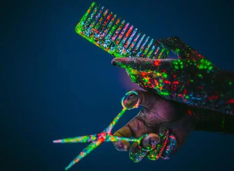 Concept. Scissors and Comb are painted in ultraviolet powder. Style and fashion Stock Photos