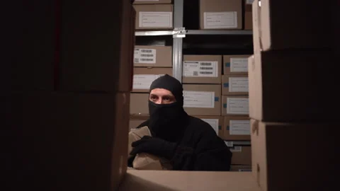 Concept of security problems in warehouses. Thief in a black mask steals boxes Stock Footage 250623362
