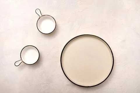 Concept set of empty plate and saucepans with black rim on light marble Stock Photos