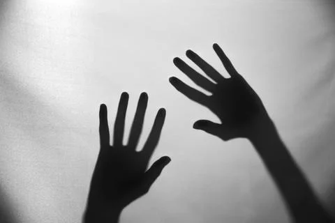 The concept of the shadow of hand behind a white cloth illuminated from behin Stock Photos