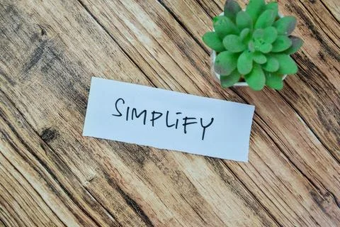 Concept of Simplify write on sticky notes isolated on Wooden Table. Stock Photos