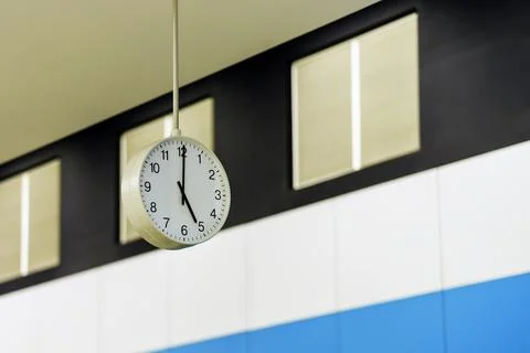 The concept of a slight delay. The clock on the ceiling shows half a minute.. Stock Photos