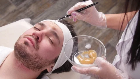 Concept of spa for men. A young man is applied a cosmetic mask on the face in a Stock Footage 102662920