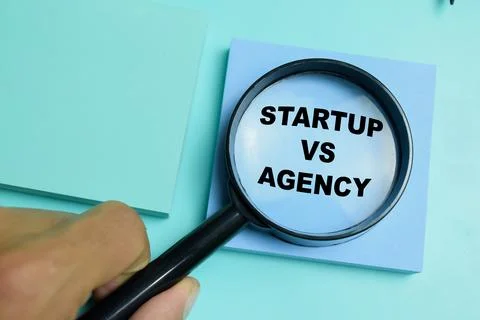 Concept of startup vs agency write on sticky notes isolated on table. Stock Photos