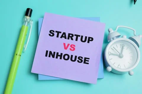 Concept of startup vs inhouse write on sticky notes isolated on table. Stock Photos