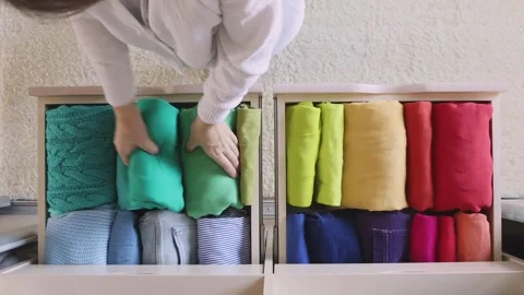 The concept of storage and organization of space. A woman takes a T-shirt from a Stock Footage 245870310