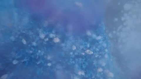The concept of substance dissolution or blue powder dissolving in water, macro s Vidéo 246972596