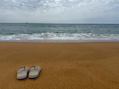 Concept of summer vacation at the beach with flip flops and ocean waves Foto stock