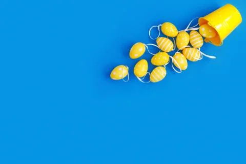Concept sweet Easter symbols colored yellow eggs and buckets on blue paper ba Stock Photos