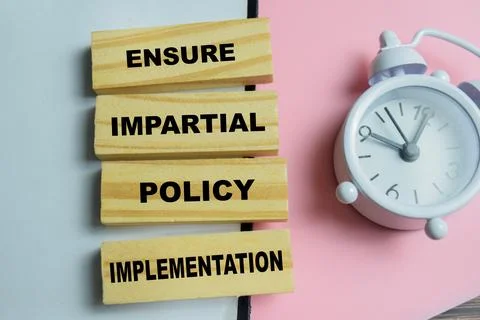 Concept of text ensure impartial policy implementation on wooden blocks. Stock Photos