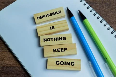 Concept of text impossible is nothing keep going on wooden blocks. Stock Photos
