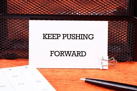 Concept text KEEP PUSHING FORWARD written on a business card next to a pen .. Stock Photos