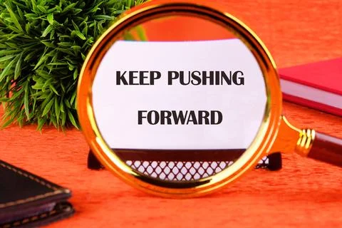 Concept text KEEP PUSHING FORWARD focuses through a magnifying glass on a bus Stock Photos