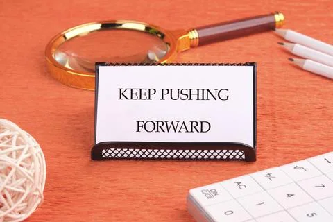 Concept text KEEP PUSHING FORWARD written on a business card on a black stand Stock Photos
