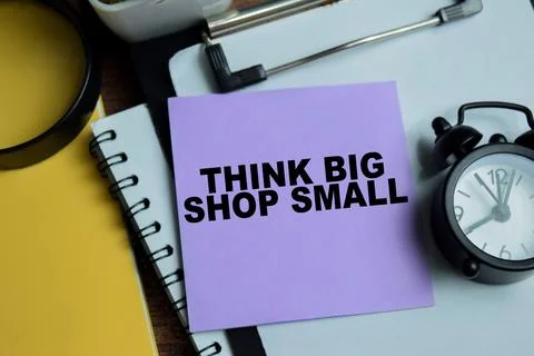 Concept of think big shop small write on sticky notes isolated on Wooden Table Stock Photos