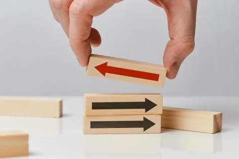 Concept of thinking differently - hand holds a wooden block with an arrow. Stock Photos
