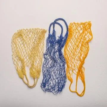 Concept of the three colored string bags made from natural materials on a light Stock Photos