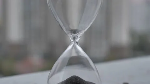 Concept Time is up. Extreme close up of a transparent hourglass with flowing Stock Footage 176264314