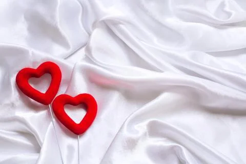 The concept of two lovers hearts lying on the white satin, can be used as a back Stock Photos