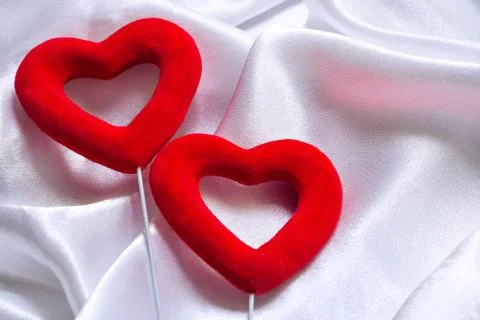 The concept of two lovers hearts lying on the white satin, can be used as a back Stock Photos