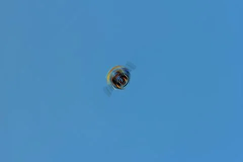 Concept of an unidentified flying colored object rotating in blue sky Stock Illustration