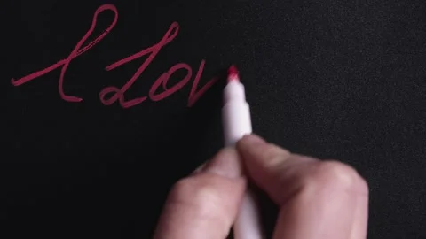 Concept of Valentine's Day. Write and draw with a red marker on a black 库存影片 145384184