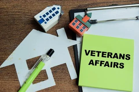 Concept of veterans affairs write on sticky notes isolated on Wooden Table. Stock Photos